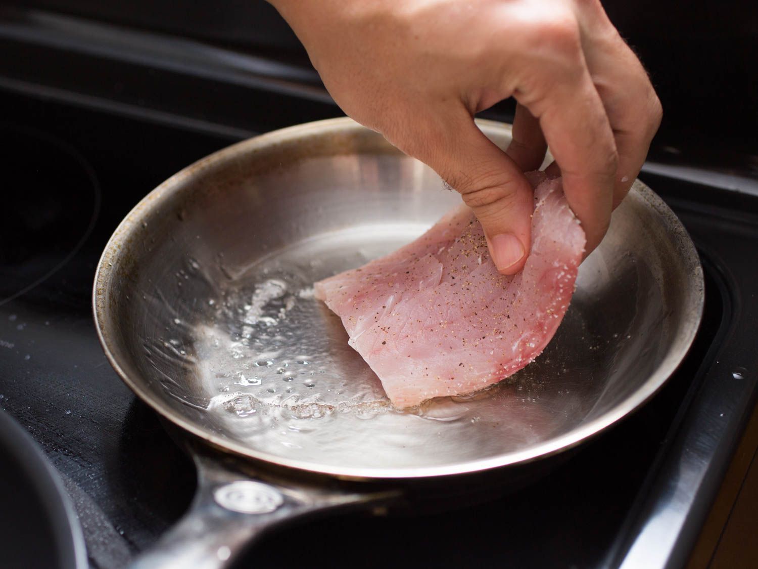 A fish fillet is added to a well-oiled pan.