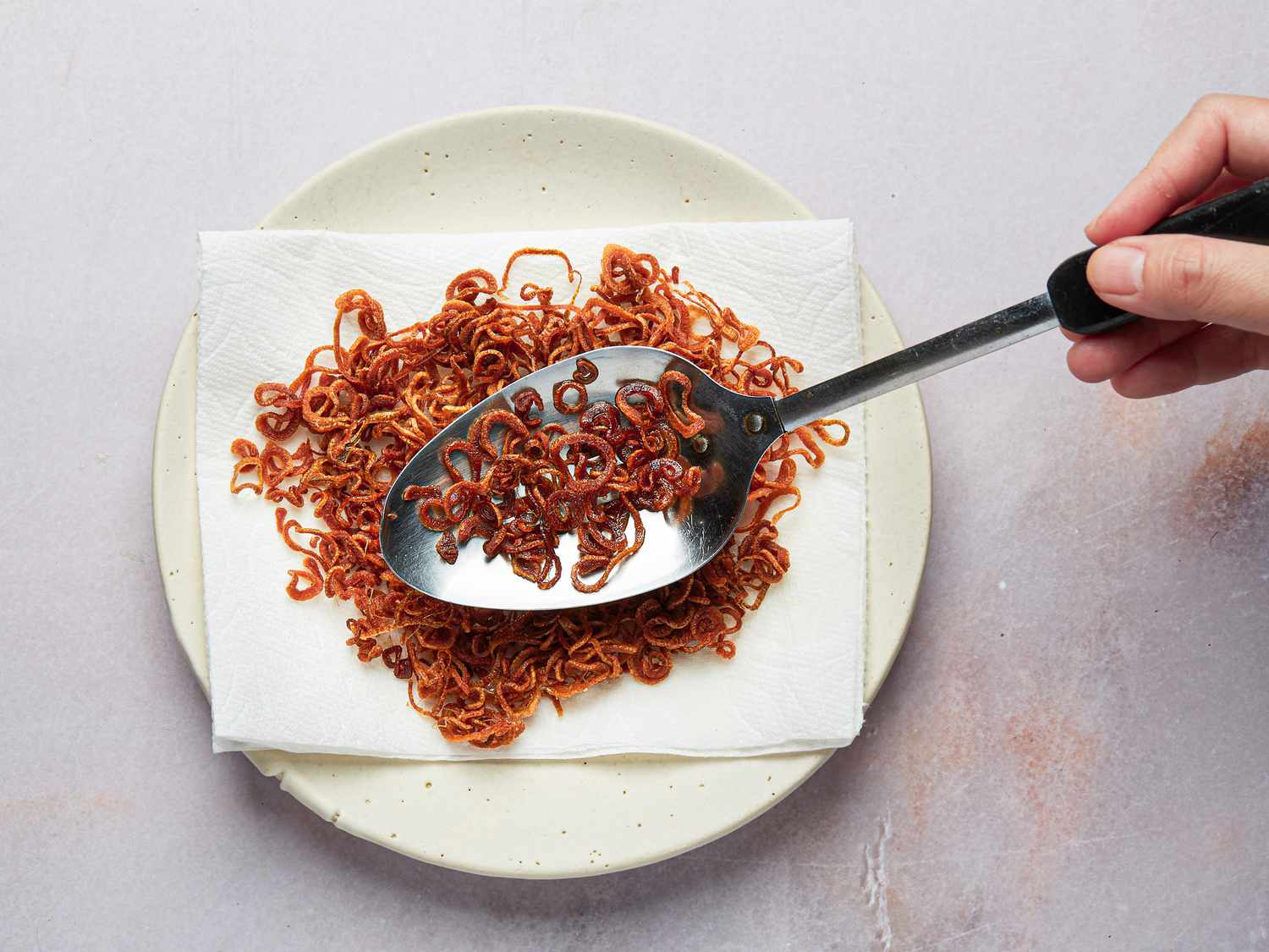 Overhead view of putting fried shallots onto a plate