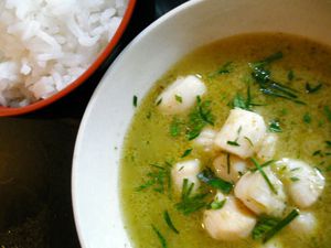Scallops in green curry sauce, served in a bowl with rice on the side.
