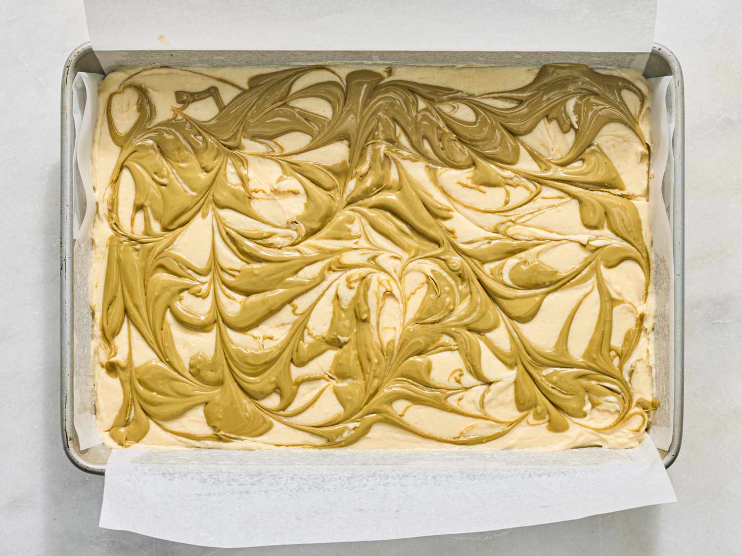 A baking tray with batter swirled with a topping ready to be baked