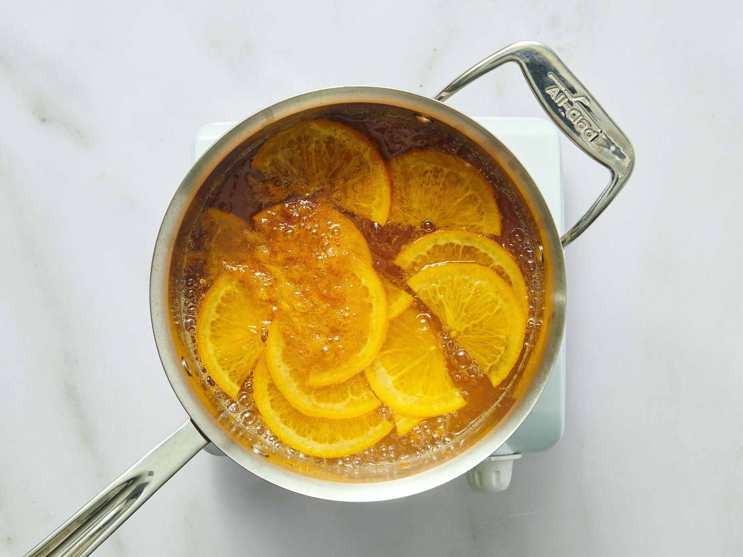 Slices of orange boiling in a pot of syrup