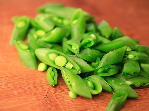Chopped snap peas on a cutting board.