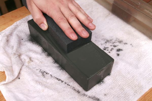 Hand using a low-grit stone fixer on a whetstone