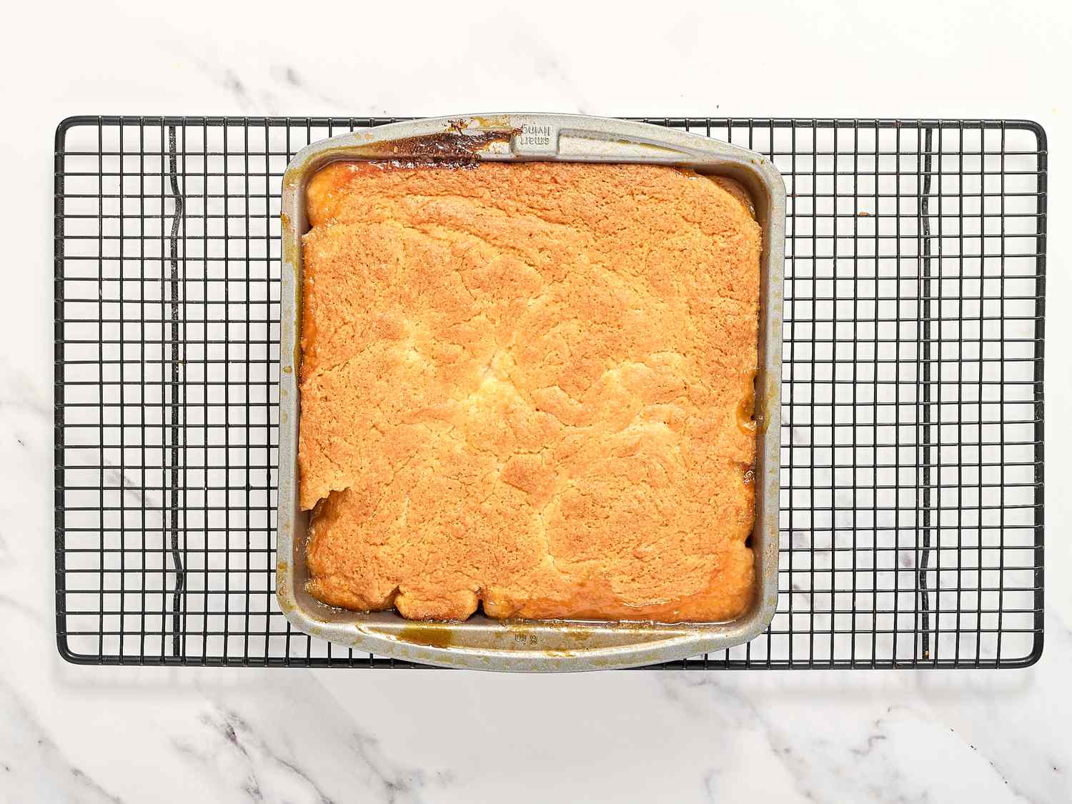 A freshly baked cobbler in a square pan placed on a wire rack