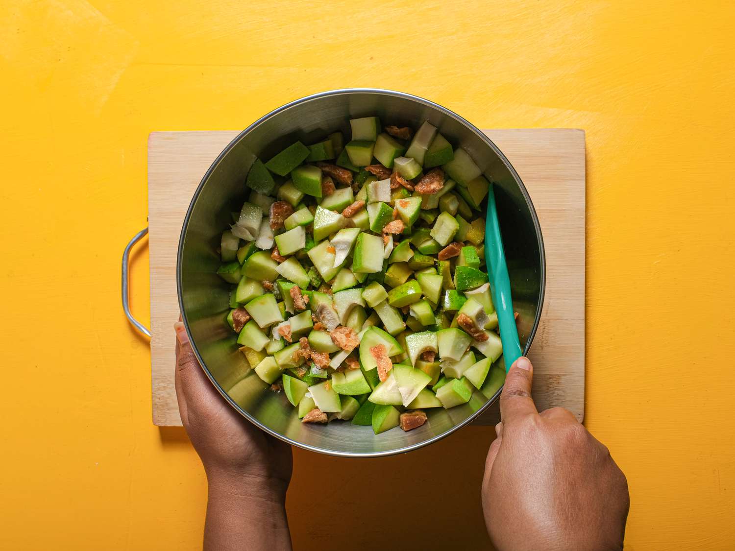 Mixing mango with sugar and salt in a metal bowl