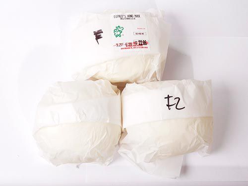 Three balls of mozzarella wrapped in paper.