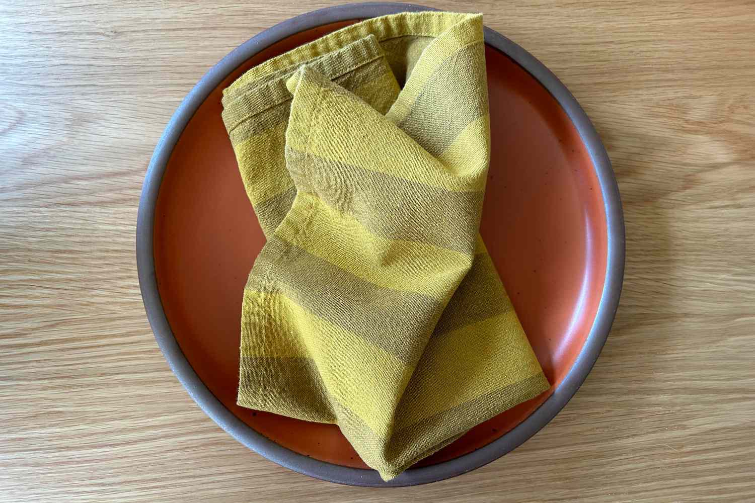 Yellow stripe cloth napkin on top of a orange plate