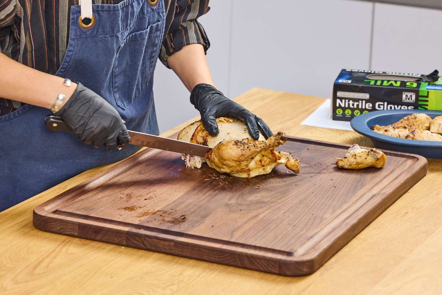 A person cuts chicken with the Wüsthof Classic 9 Inch Hollow Edge Carving Knife