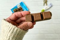 A hand holding pieces of Ritter Sport Alpine Milk Chocolate