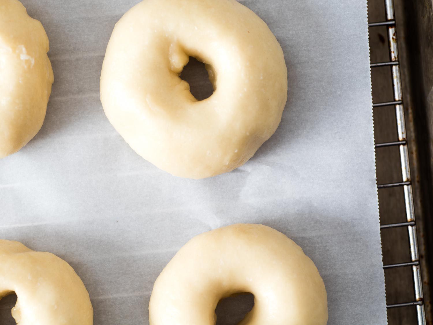 Close overhead view of mini bagels on a parchment-lined cooling rack, ready to be baked.