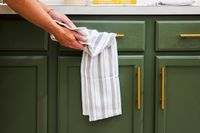 A person drying their hands on a striped dish towel.