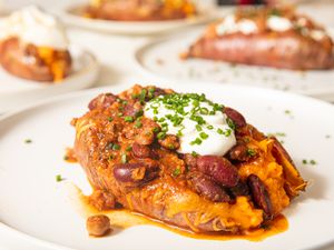 Side view of loaded backed sweet potato topped with cheese and beans 
