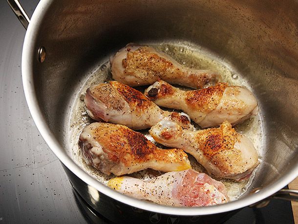 Browning seasoned and spice-rubbed chicken drumsticks in a stock pot with oil.