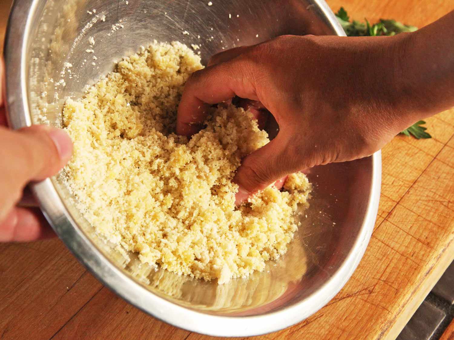 Combining bread crumbs with cheese and herbs in a mixing bowl. 