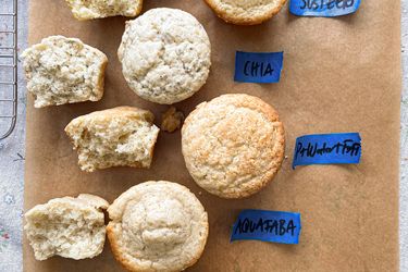 A comparison of muffins made with different egg substitutes labeled Egg Chia Aquafaba and Flax on parchment paper