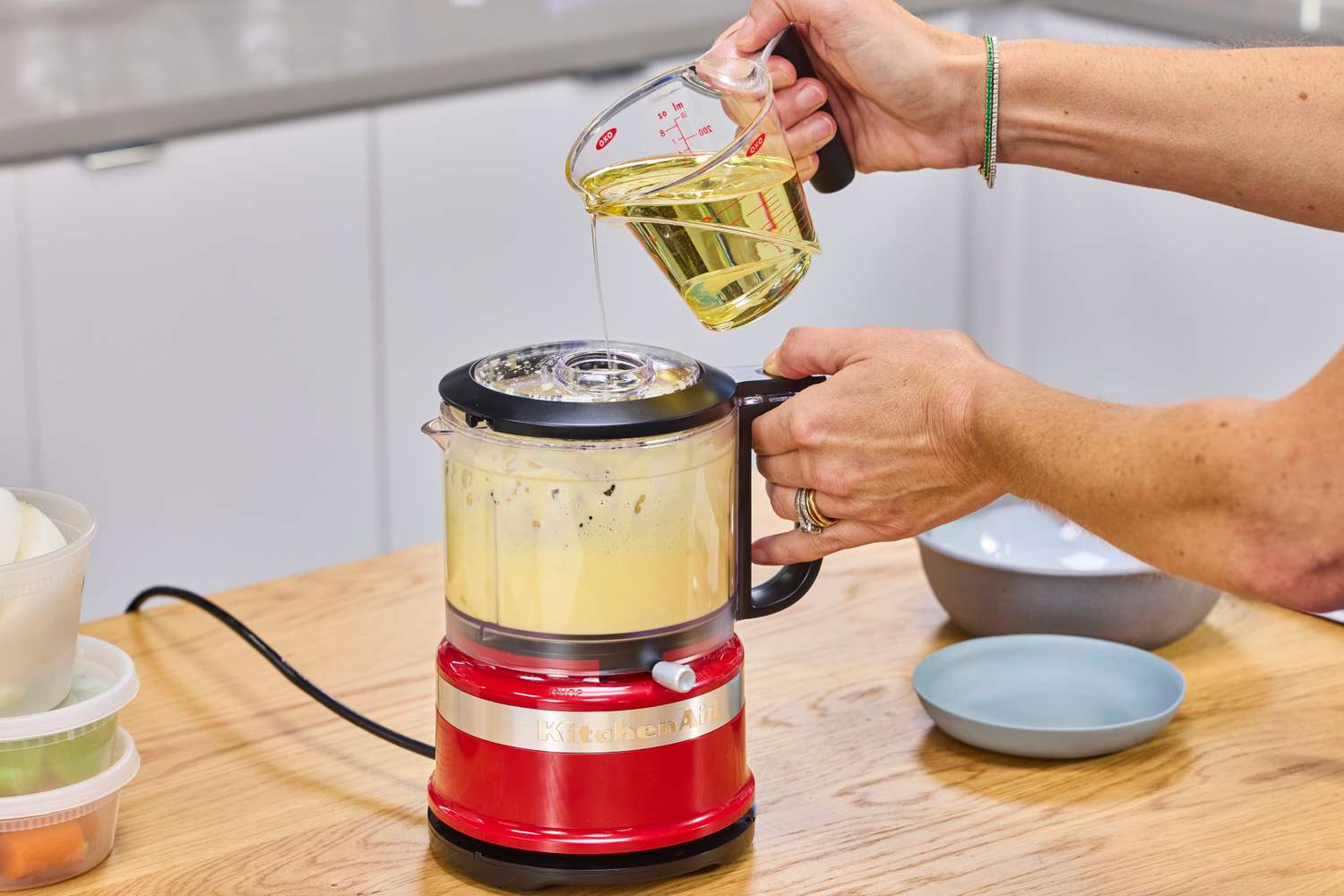 A person pours oil into the KitchenAid 3.5-Cup Food Chopper