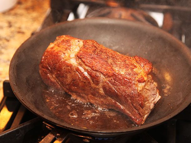 Searing sous vide double-cut pork chop in a pan. The chop looks golden brown. 