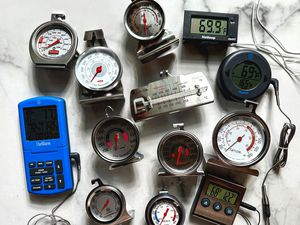 A collection of oven thermometers on a marble surface.