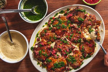 Platter of smashed double sauce potatoes with garnishes on a wooden table