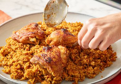 Chicken over rice being garnished with a spoon
