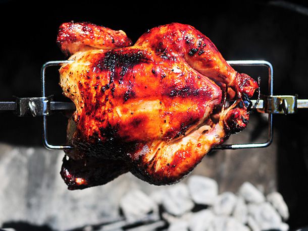 A mojo-marinated chicken suspended on a spit over coals.