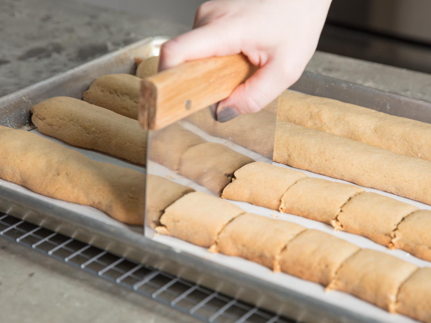 Cutting fig newton strips with a bench scraper hot out of the oven.