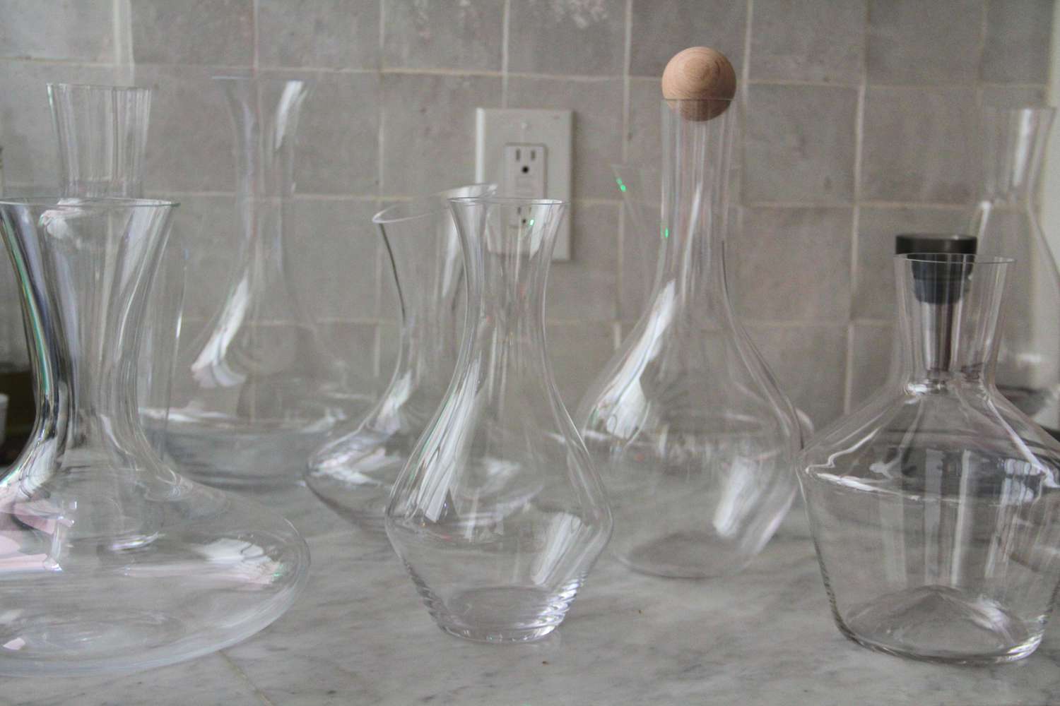 A collection of empty wine decanters on a marble counter