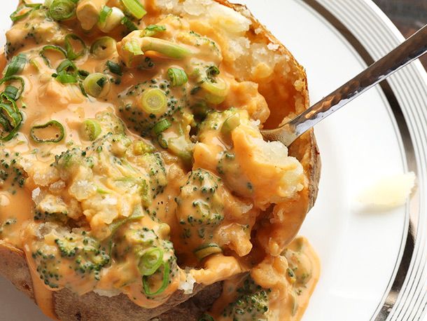 Digging into a baked potato loaded with broccoli, scallions, and vegan nacho cheese