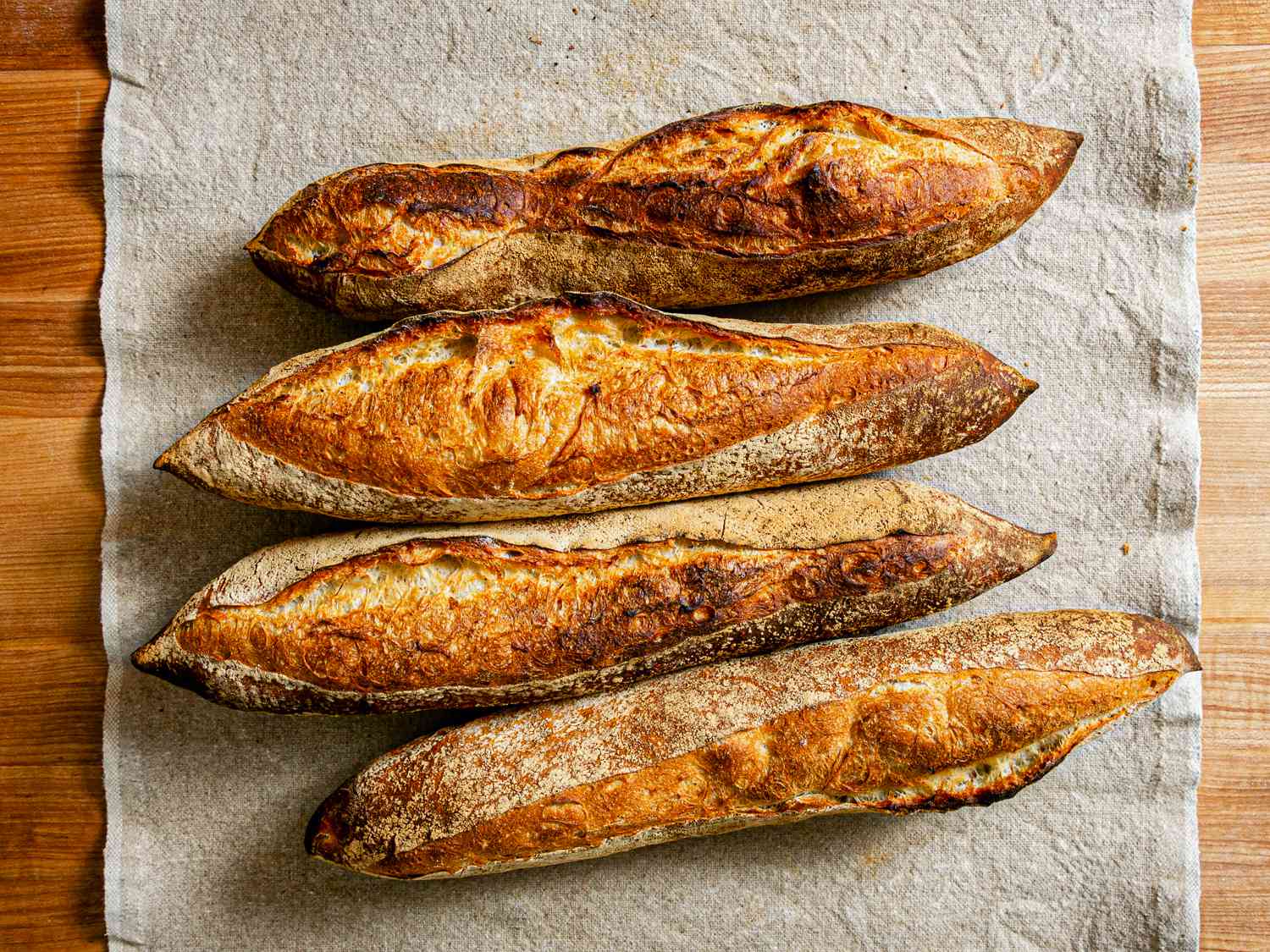 Overhead view of 4 baguettes on a grey table runner.