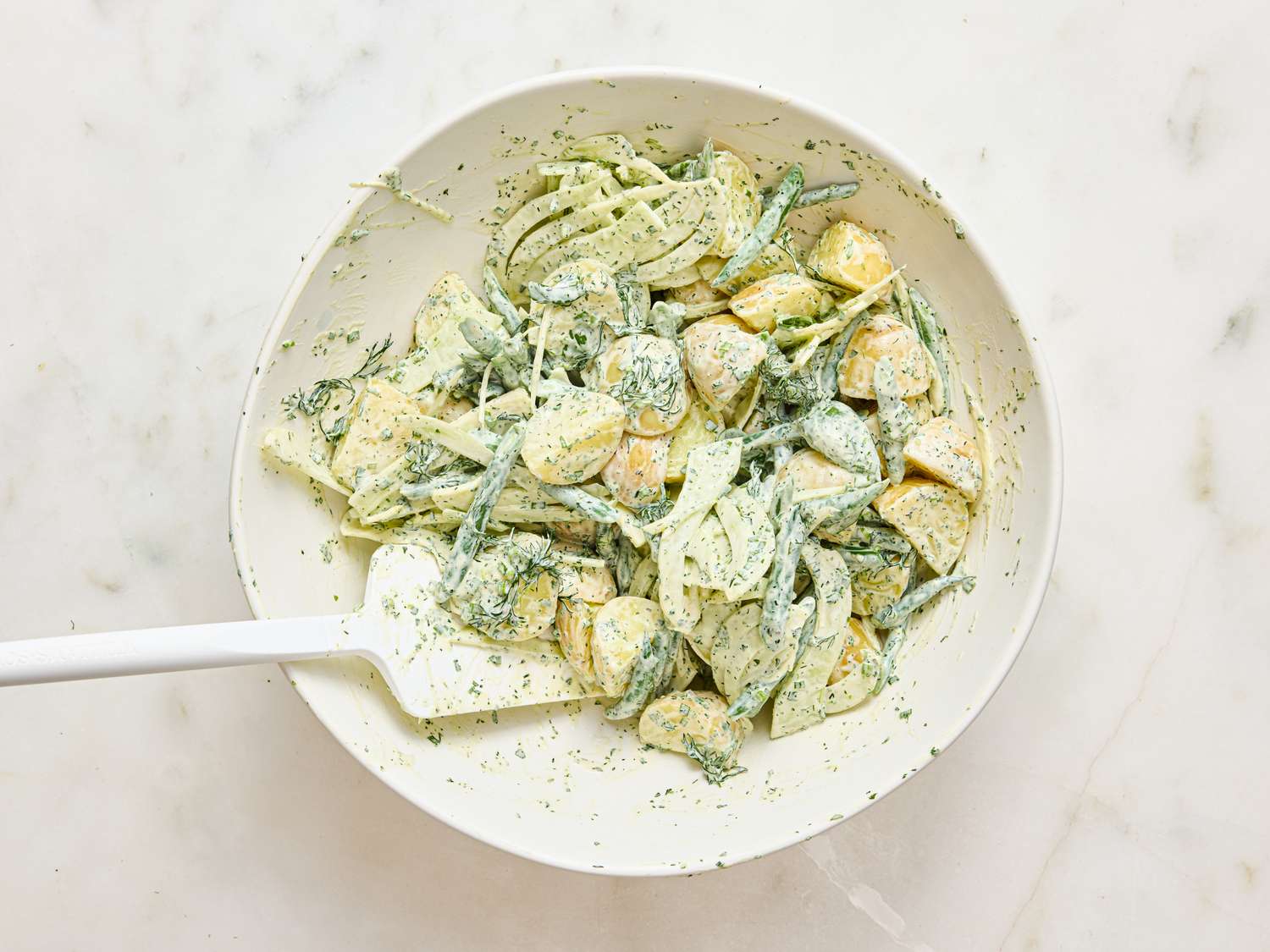 Prepared Green Goddess potato salad in a bowl with a spatula