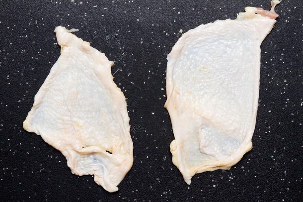 Two pieces of raw chicken skin spread flat on a work surface