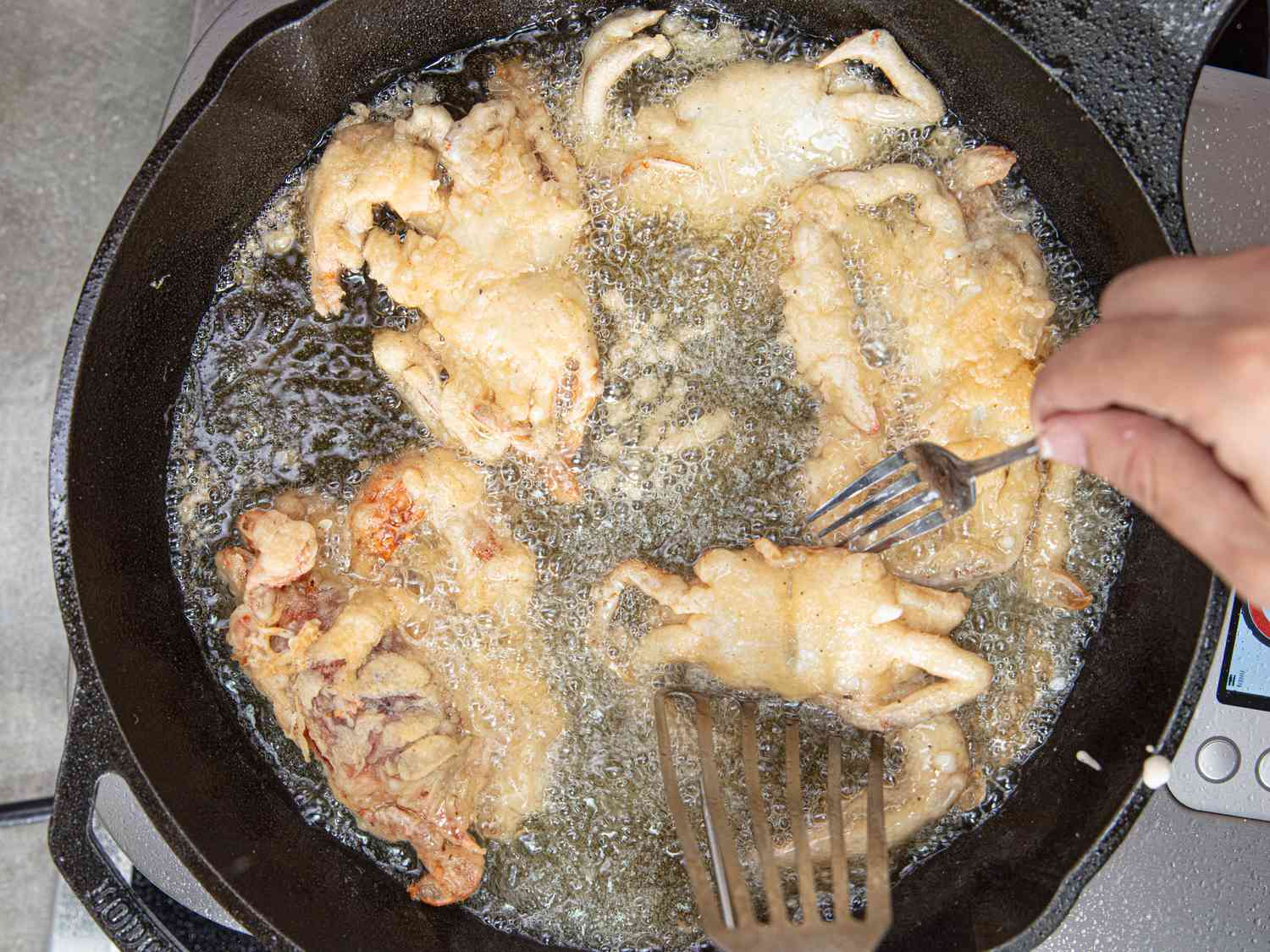 Overhead view of frying crabs in a cast iron skillet.