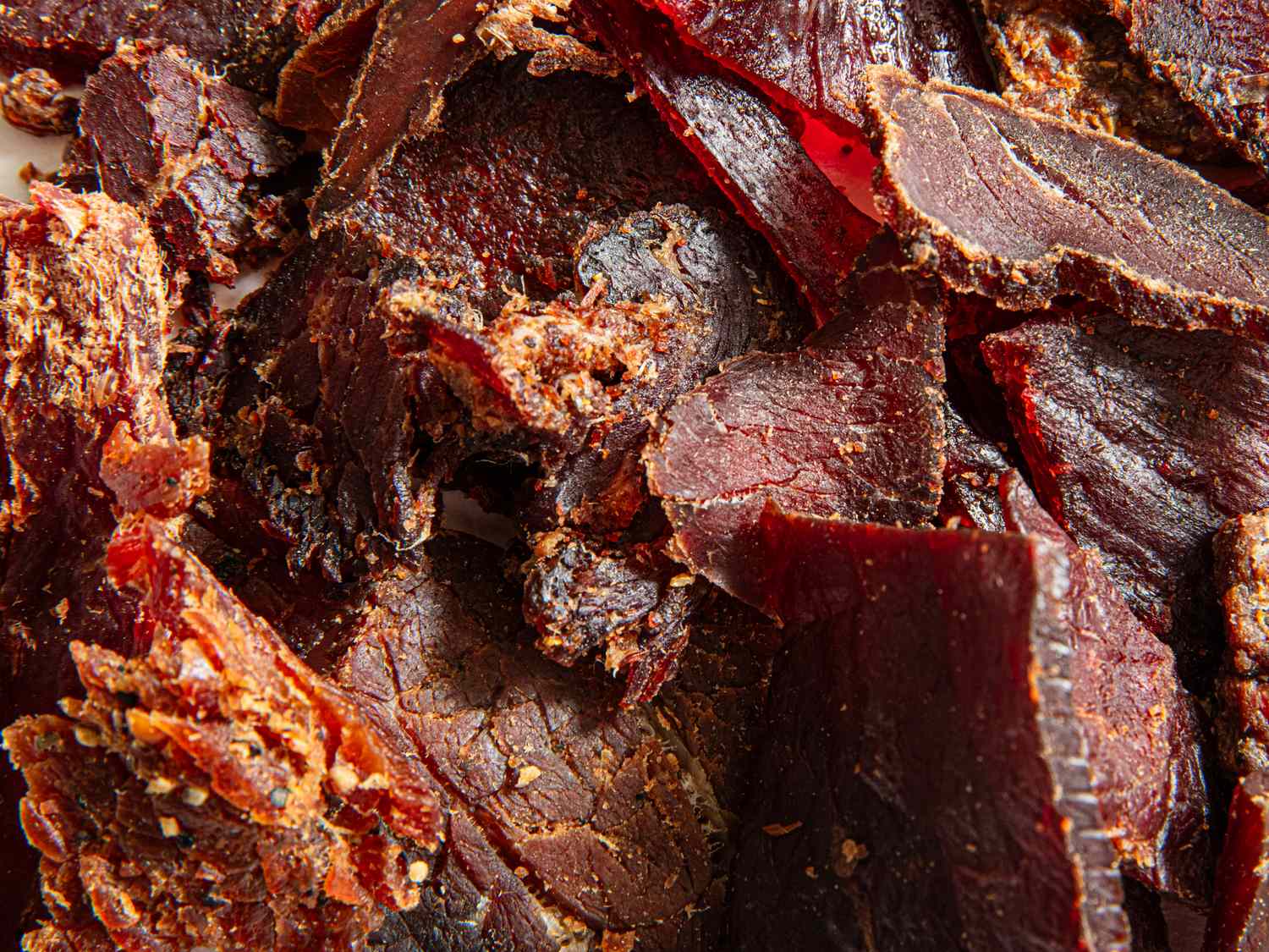 Closeup of thinly sliced beef jerky pieces with seasoning visible on the surface
