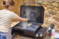 A person butters the top of the Weber Slate 22 inch Rust-Resistant Tabletop Griddle