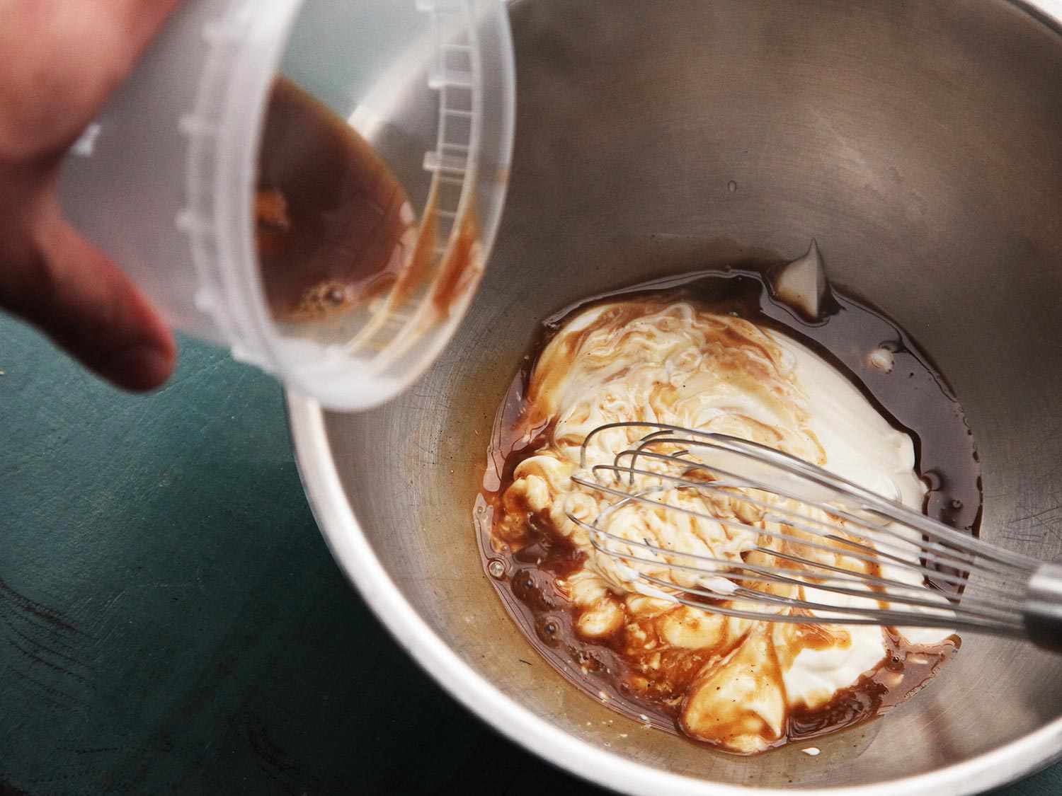 Combining broth with sour cream in a bowl with a whisk. 