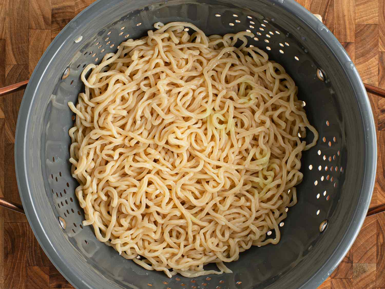 Drained al dente noodles in a colander after being rinsed with cold water.