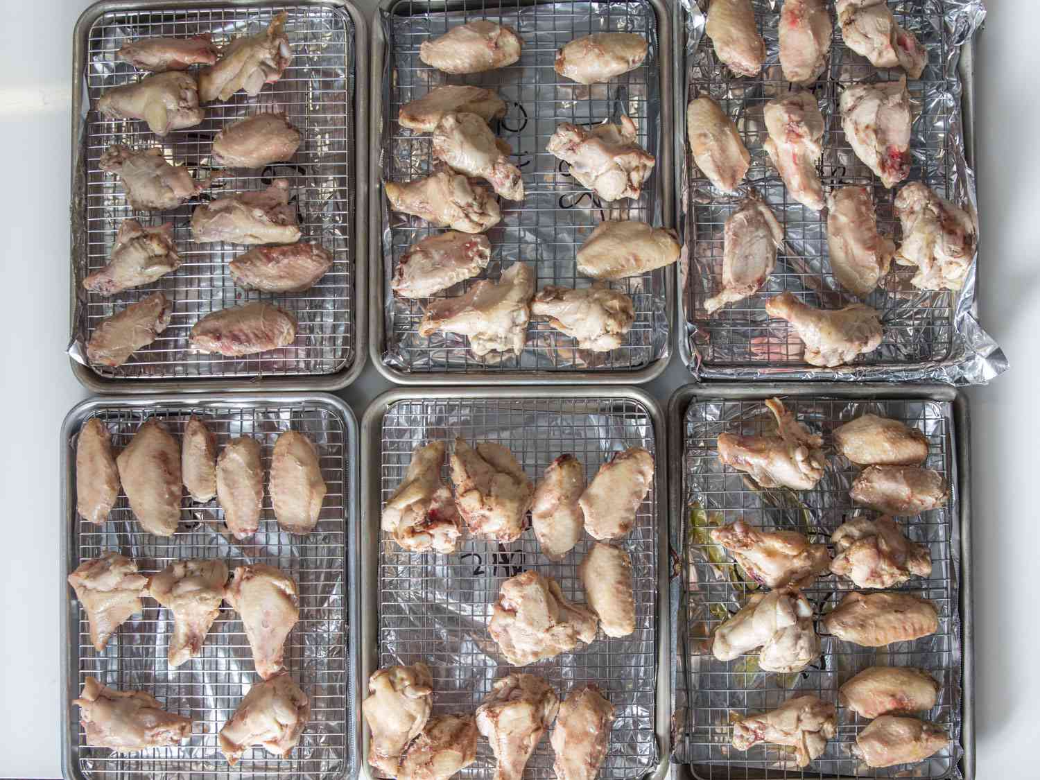 Sous vide chicken wings arranged on wire racks over foil-lined baking sheets.