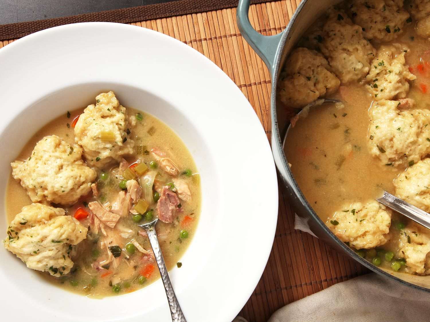 Overhead of pot and serving bowl of turkey matzoh ball soup.