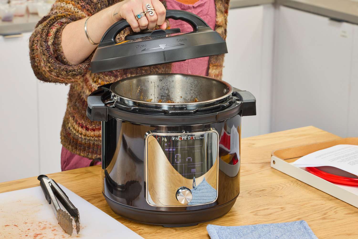 A person lifts the lid of the Instant Pot Pro Plus Wi-Fi Smart 10-in-1 6-Quart Pressure Cooker