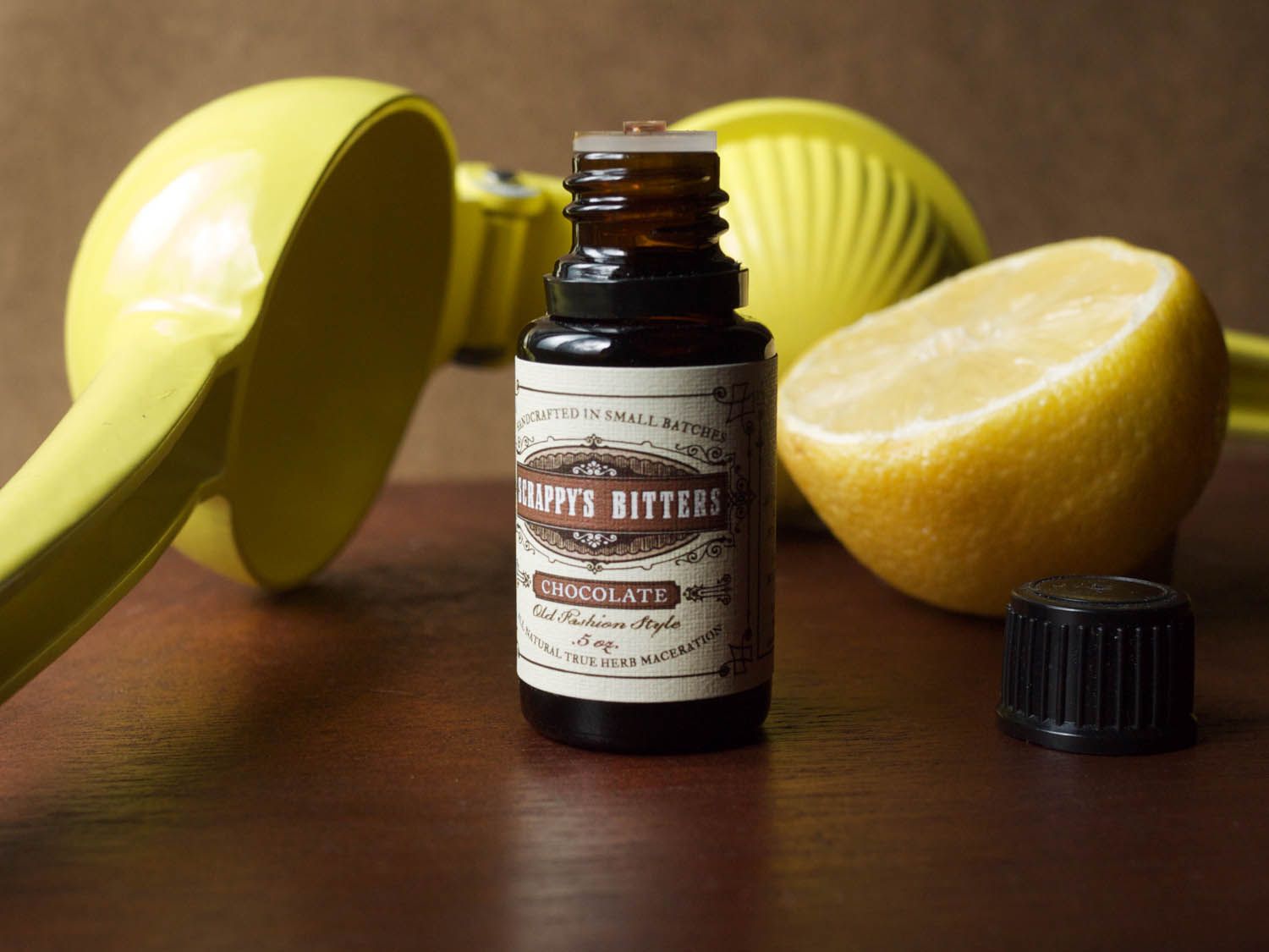 Bottle of chocolate bitters with fresh half lemon and citrus juicer