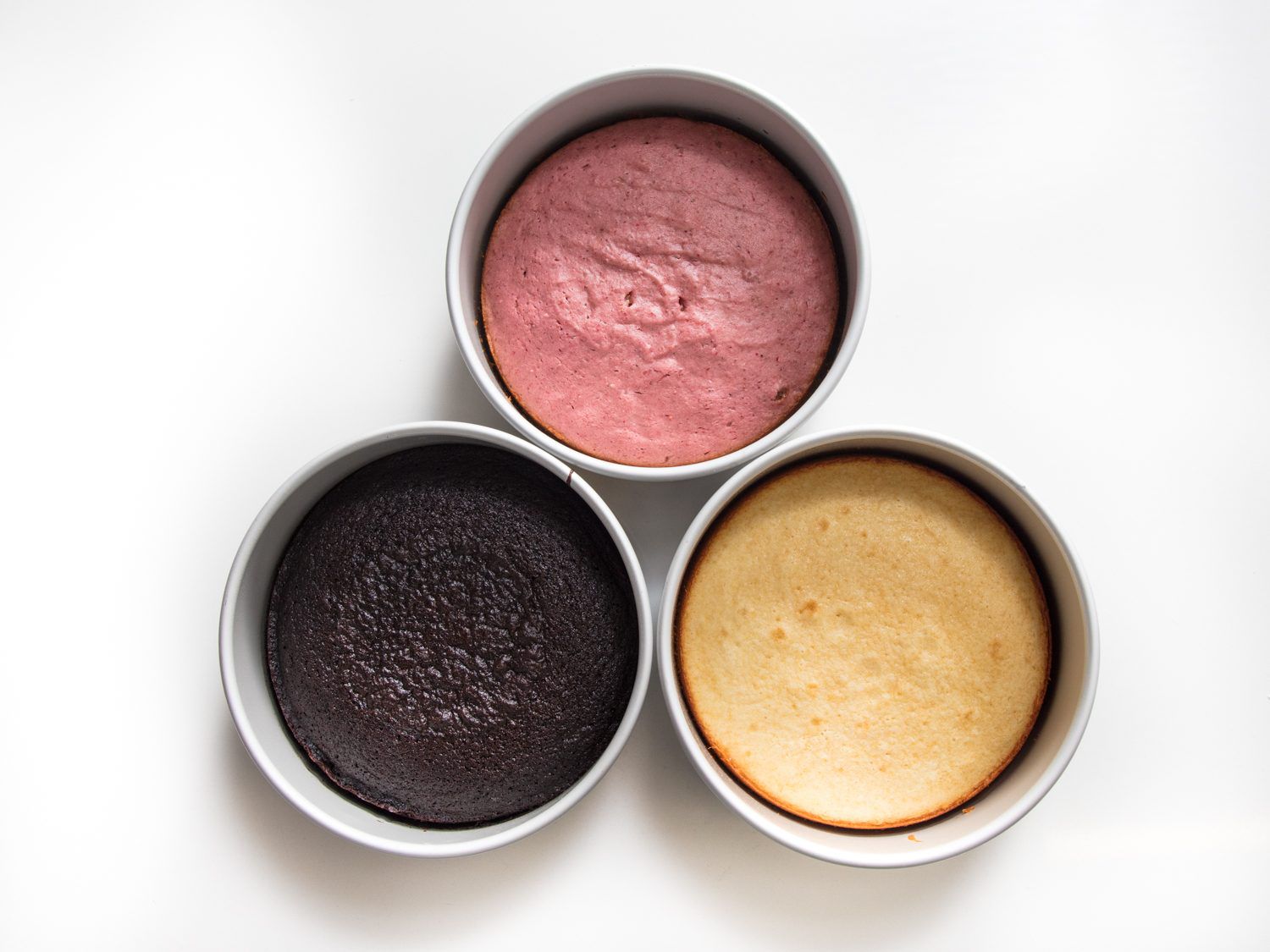 Overhead shot of Neapolitan cake layers in 3 round pans. 