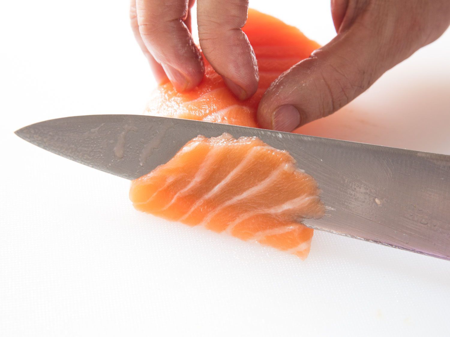 Thinly slicing salmon for tiradito.