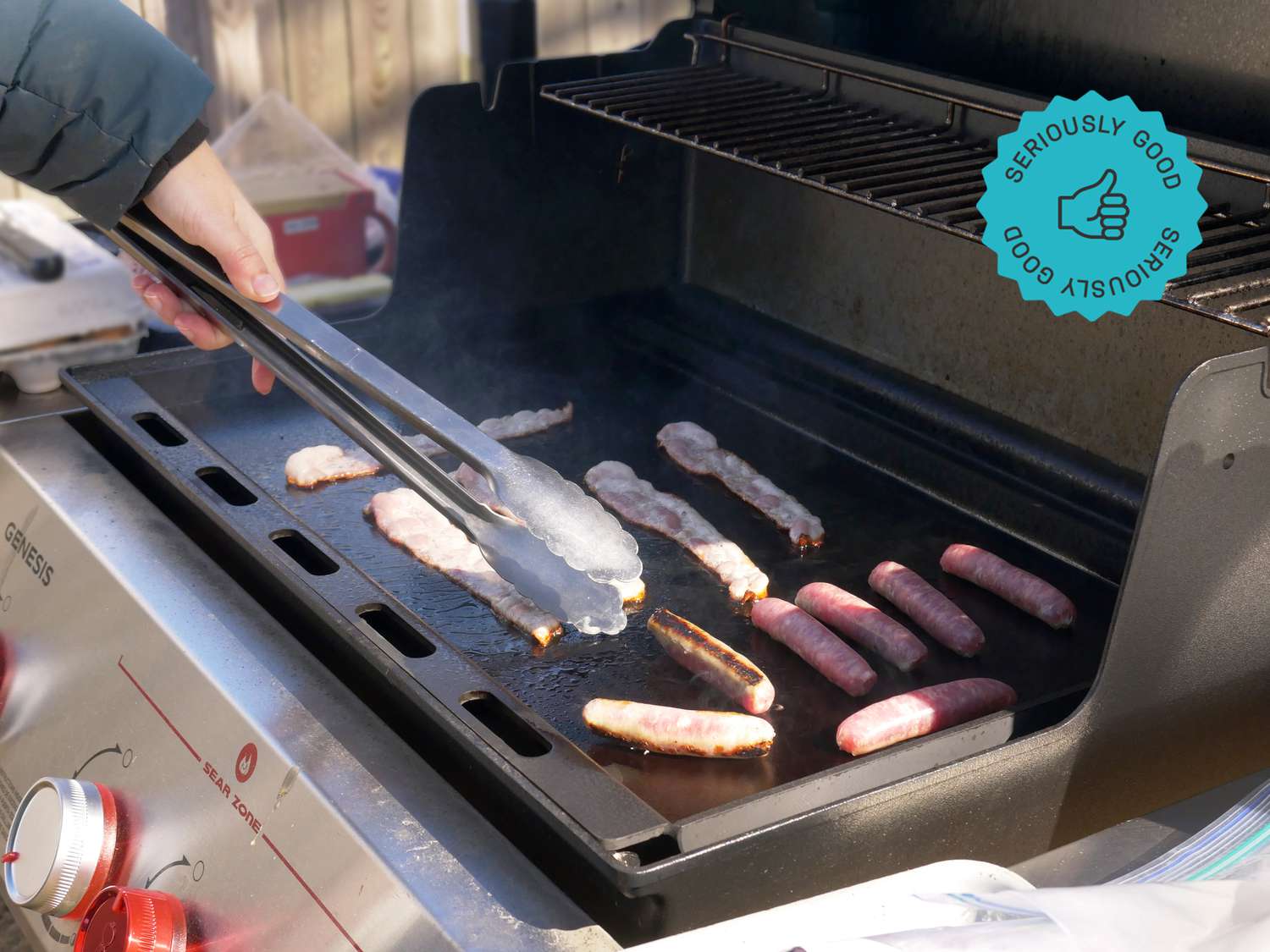 a person flipping sausages on the weber griddle insert