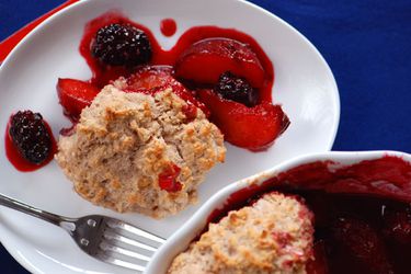 Closeup of blackberry-plum cobbler, served on a white plate from the baking dish.