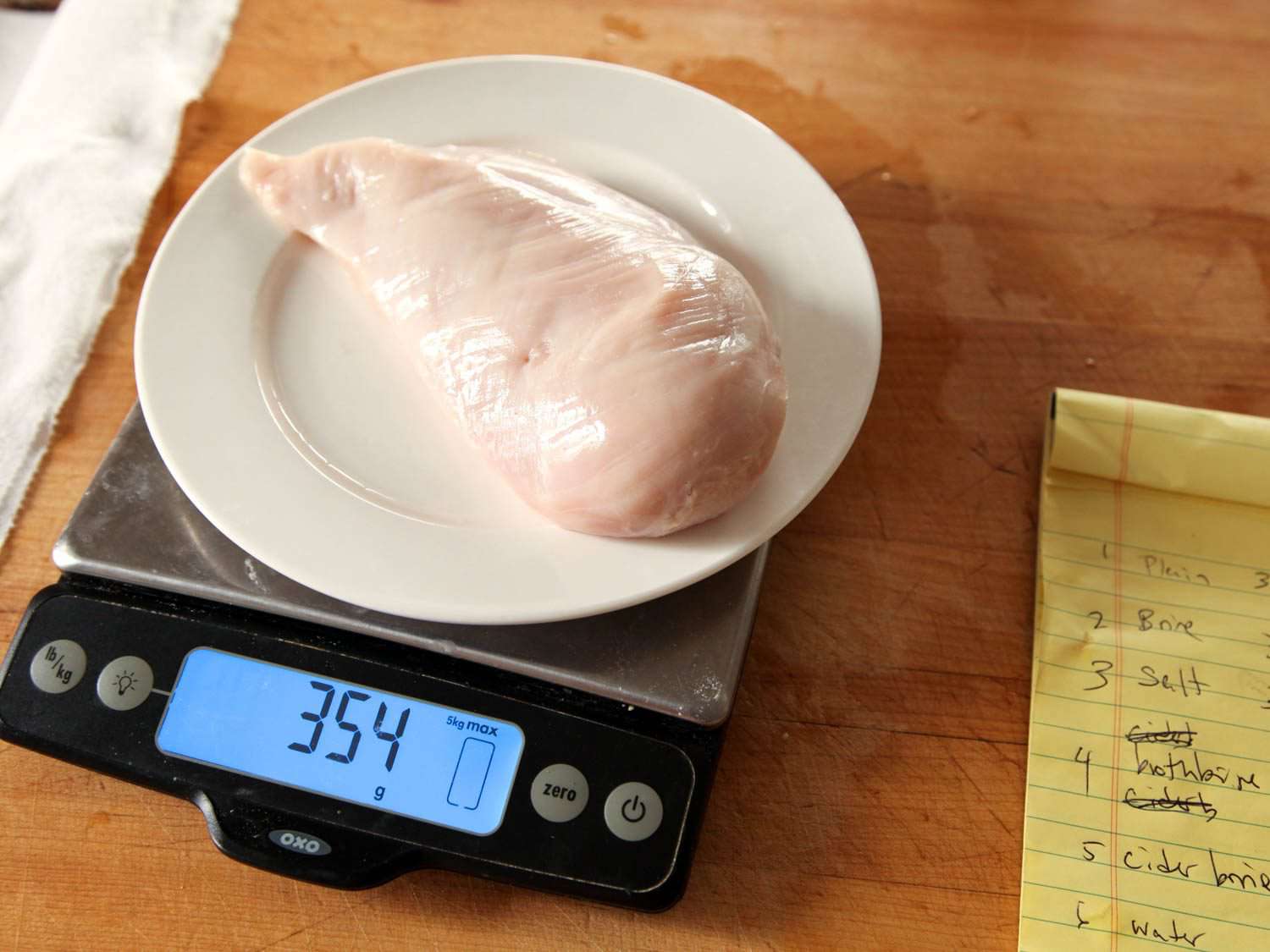Raw chicken on kitchen scale, showing water retention from brine.
