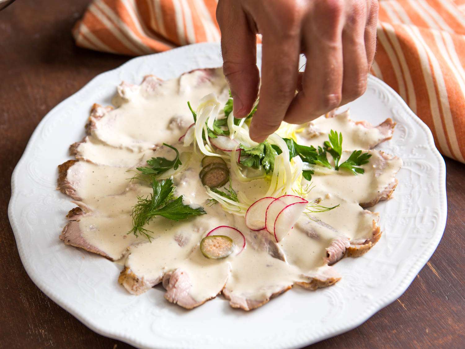 Garnish pork tenderloin vitello tonnato with radish slices, parsley, and thinly sliced fennel. 
