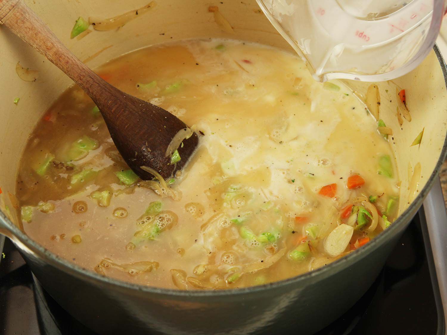 Pouring water or chicken stock into the Dutch oven.