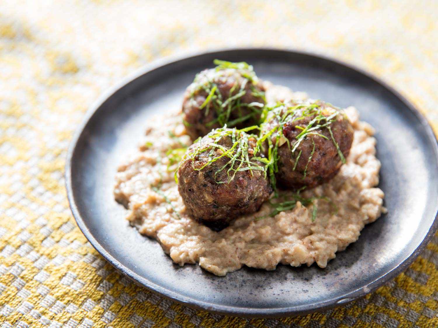A platter of smoky lamb meatballs on a bed of baba ganoush.