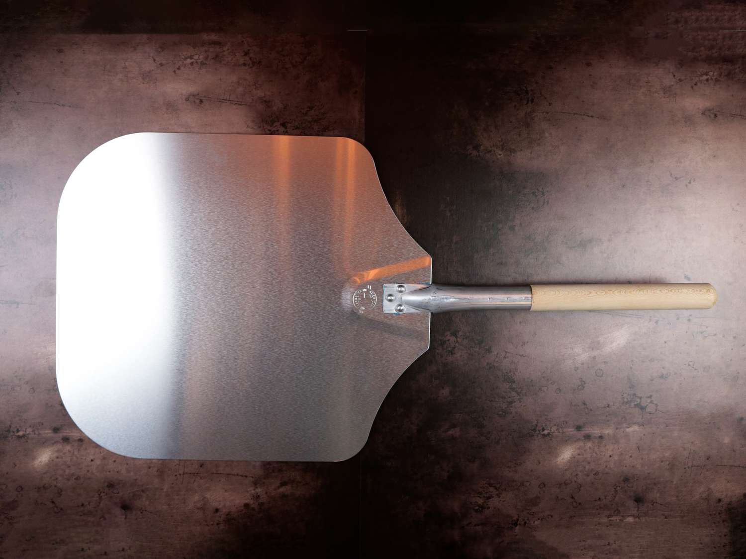 A metal pizza peel on a dark background