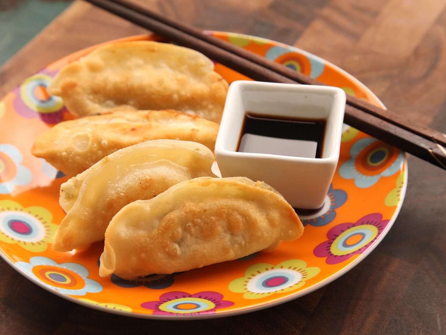 Dumplings and dipping sauce on a serving plate.
